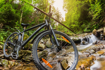 Fototapeta na wymiar Mountain bike standing on a forest river stream.