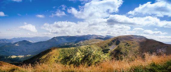 Landscape photo of mountain hills with blue sunny day sky.
