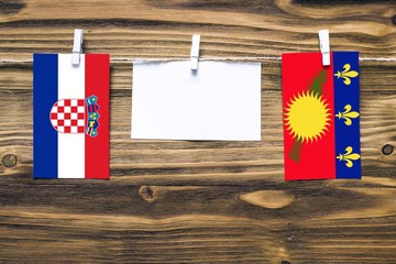 Hanging flags of Croatia and Guadeloupe attached to rope with clothes pins with copy space on white...