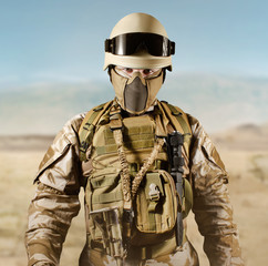 Soldier in uniform standing in desert.