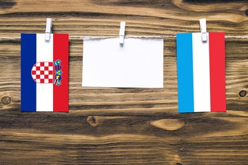 Hanging flags of Croatia and Luxembourg attached to rope with clothes pins with copy space on white...