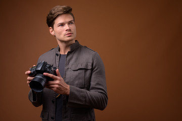 Studio shot of young handsome man as photographer with camera