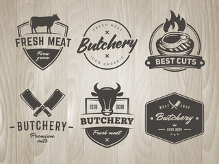 Butchery labels and logos. Vector BBQ, grill, meat, barbecue, steak badges and stickers. Retro emblems for steak house or grill bar on vintage wooden background
