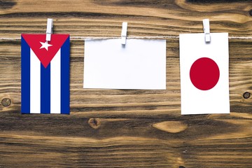 Hanging flags of Cuba and Japan attached to rope with clothes pins with copy space on white note...