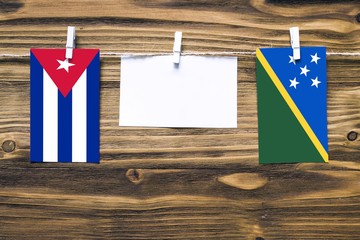 Hanging flags of Cuba and Solomon Islands attached to rope with clothes pins with copy space on...