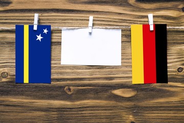 Hanging flags of Curacao and Germany attached to rope with clothes pins with copy space on white...