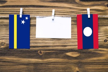 Hanging flags of Curacao and Laos attached to rope with clothes pins with copy space on white note...