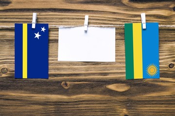 Hanging flags of Curacao and Rwanda attached to rope with clothes pins with copy space on white...
