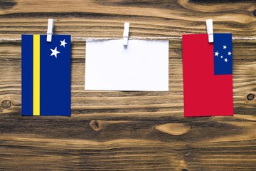 Hanging flags of Curacao and Samoa attached to rope with clothes pins with copy space on white note...