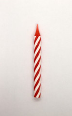 This is a photograph of a Red and White striped candle isolated on a White background