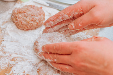 Woman cooks meat cutlets. Raw meatballs on a cutting board. Process of cooking meatballs.