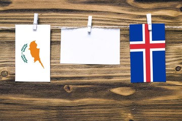 Hanging flags of Cyprus and Iceland attached to rope with clothes pins with copy space on white...