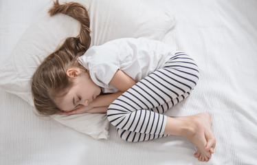 Cute little girl with long hair sleeping in bed.