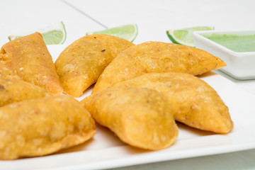 Colombian empanadas, chili and lemon on white wooden boards