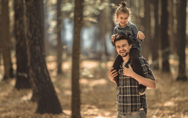 Dad and daughter walking in the autumn forest.