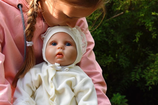 Child girl hugs her favorite doll. The doll is like a living child.