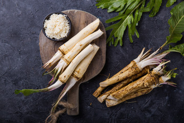 Fresh orgaanic horseradish or Horse-radish root on wooden cutting board.  top view