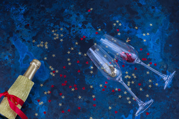 Fototapeta premium champagne bottle, two glasses and confetti on a dark blue background