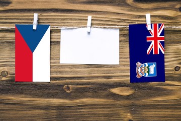 Hanging flags of Czech Republic and Falkland Islands attached to rope with clothes pins with copy...