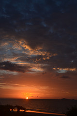 Crimson Tropical sunrise seascape with pink tinged dark nimbostratus cloud. Huay Yang, Thailand.