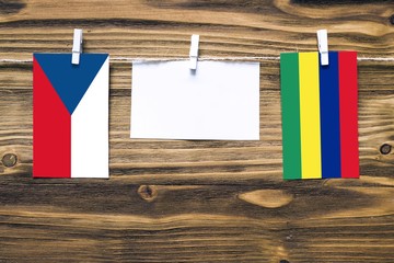 Hanging flags of Czech Republic and Mauritius attached to rope with clothes pins with copy space on white note paper on wooden background.Diplomatic relations between countries.