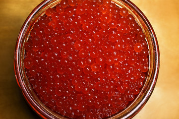 Glass jar with red caviar on a wooden surface. Horizontal photography