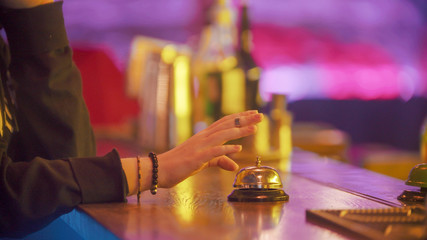 A person rings the bell on the bartender stand
