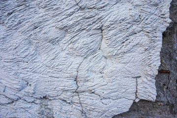 cracked concrete relief wall covered with gray cement surface as background