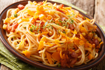 Hot Italian spaghetti with bacon, corn and Mimolette cheese close-up on a plate. horizontal