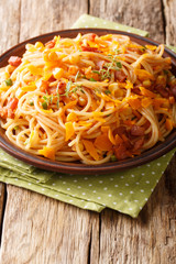 Spaghetti pasta with bacon, corn and cheese close-up on a plate. vertical