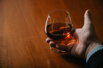 Hand holds glass with cognac close-up
