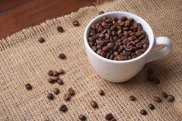 Fototapeta na wymiar cup full of coffee beans on jute