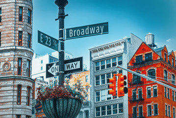 Street sign (nameplate) of Broadway and East 23 th Street and urban cityscape of New York. Midtown district.