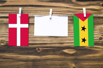 Hanging flags of Denmark and Sao Tome And Principe attached to rope with clothes pins with copy...