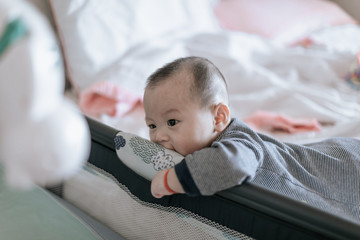 Cute asian baby trying to get out of bed in the morning