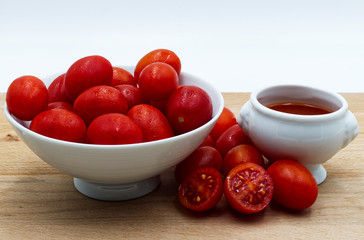 Red fresh tomatoes on wooden table, white background