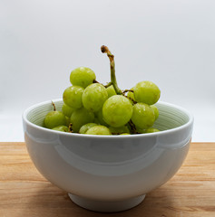 Green grape in a jar on wooden table, white background