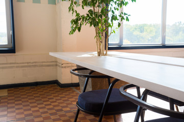 Loft style office with white brick walls and concrete columns. There is a meeting area with a large white table with black chairs