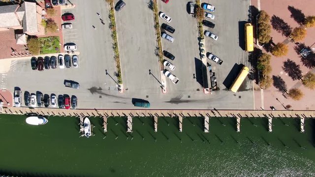 Top down aerial of empty boat docks in harbor, green water, parking lot, school bus