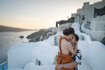 Fototapeta na wymiar Asian Couple kissing and enjoying view Oia village in Santorini island, Greece.
