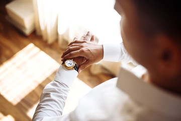Men's wrist watch, the man is watching the time. Businessman clock, businessman checking time on his wristwatch. Groom's hands in a suit adjusting wristwatch, wedding preparations, groom accessories.