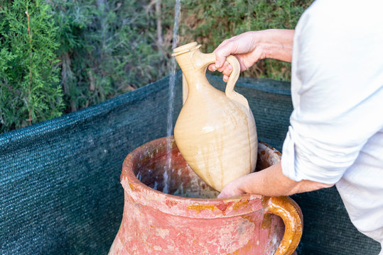 Mujer llena el c&aacute;ntaro de agua