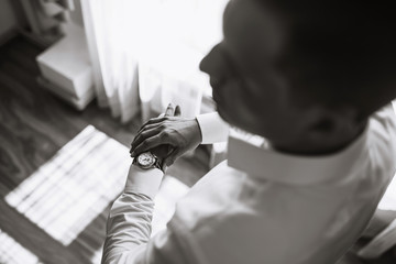 Men's wrist watch, the man is watching the time. Businessman clock, businessman checking time on his wristwatch. Groom's hands in a suit adjusting wristwatch, wedding preparations, groom accessories.