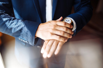 Men's wrist watch, the man is watching the time. Businessman clock, businessman checking time on his wristwatch. Groom's hands in a suit adjusting wristwatch, wedding preparations, groom accessories.