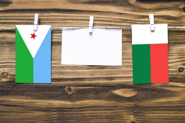 Hanging flags of Djibouti and Madagascar attached to rope with clothes pins with copy space on...