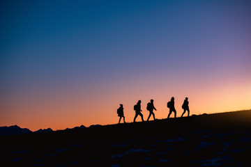Group of hikers at sunset mountain - obrazy, fototapety, plakaty