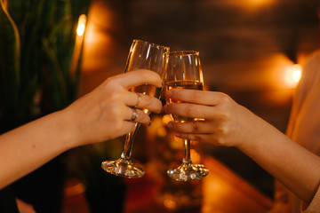 Close-up of two glasses of Champagne clinking together on festive bright background. Celebration on New Year