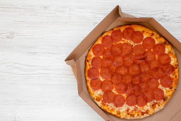 Homemade Pepperoni pizza in a box on a white wooden background, top view. Overhead, from above, flat lay. Copy space.