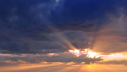 The last rays of the sun at sunset in the clouds