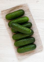 Fresh organic mini baby cucumbers on a white wooden surface, top view. Flat lay, overhead, from above. Close-up.